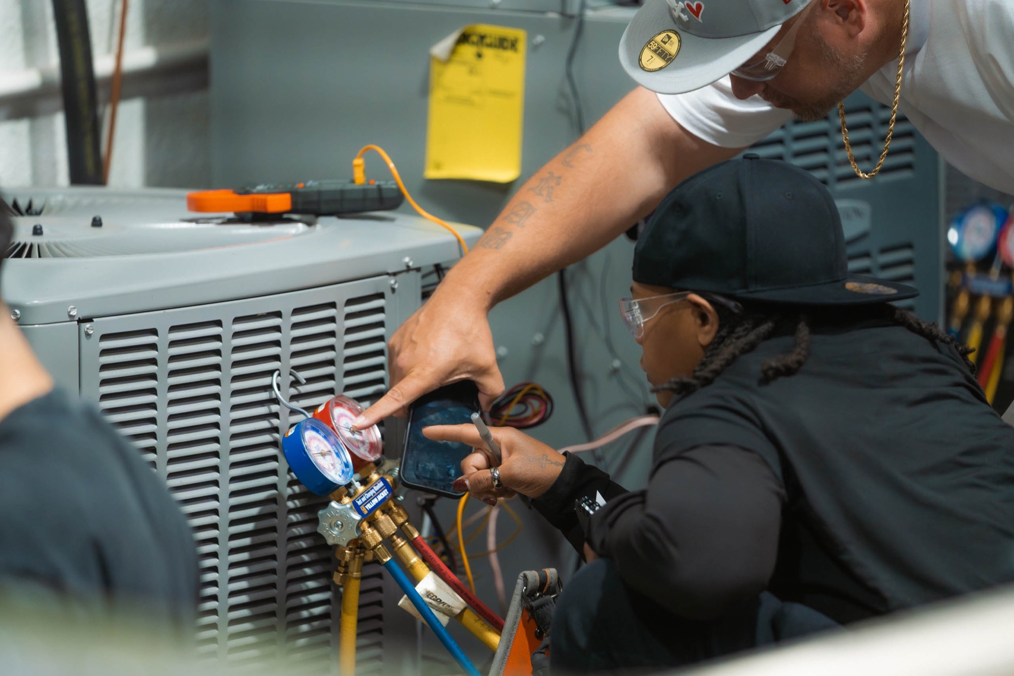 An HVAC instructor coaching an adult student through reading system gauges
